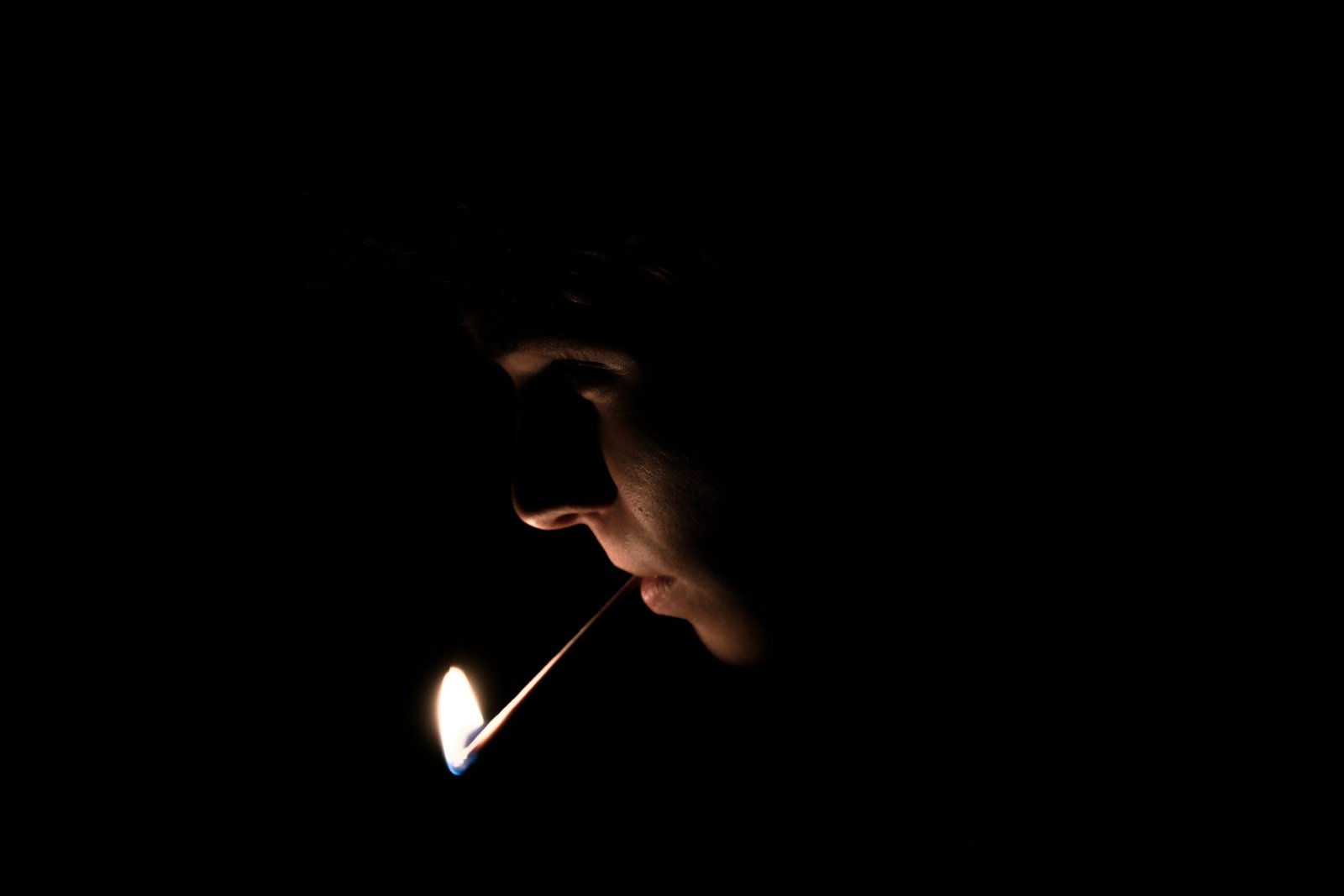 man with lighted matchstick on his mouth